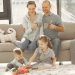 Cheerful family wearing casual clothes sitting in living room while playing and drinking tea during weekend at home in morning