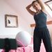 Woman stretching in a cozy room, surrounded by fitness equipment, engaging in a home workout session.