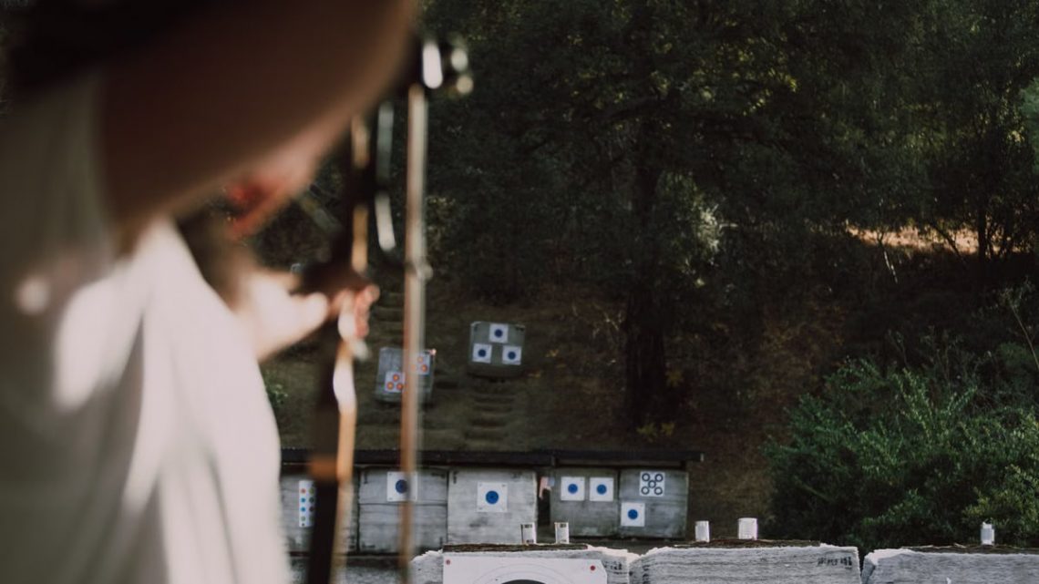 Focused archer aims at colorful targets in an outdoor forest range.