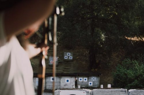 Focused archer aims at colorful targets in an outdoor forest range.